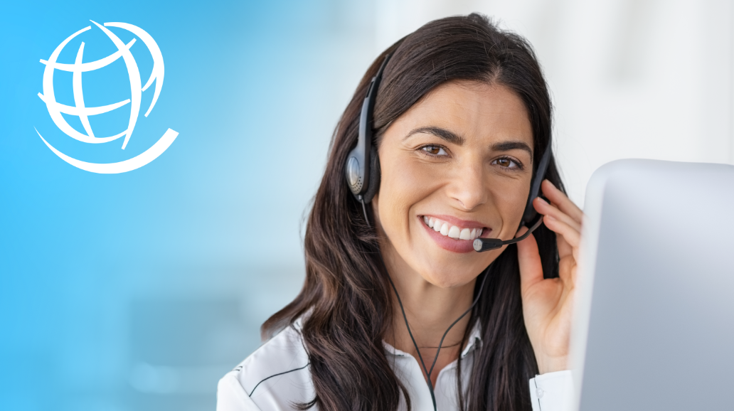 A woman smiles as she talks on the phone through a head set.