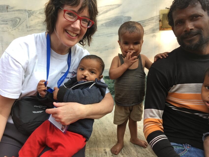 Female volunteer with two young children with cleft and their father.