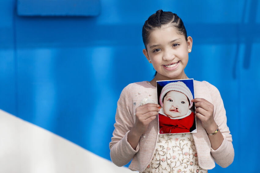 Young girl holds photo of herself as a baby.