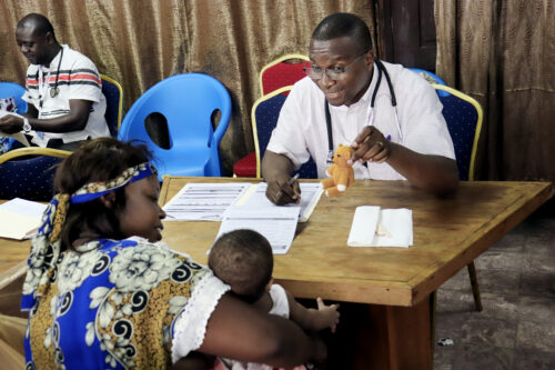 An Operation Smile DRC volunteer shows a crocheted bear to a patient to make them smile.