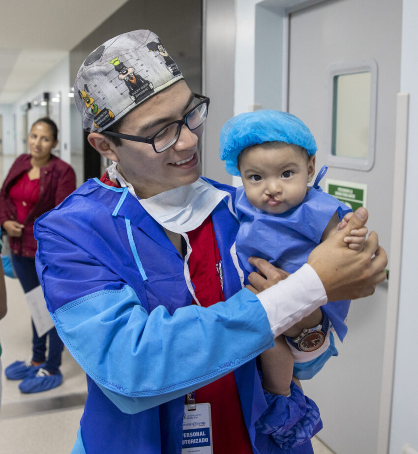 Medical professional comforts baby as they approach the operating room.