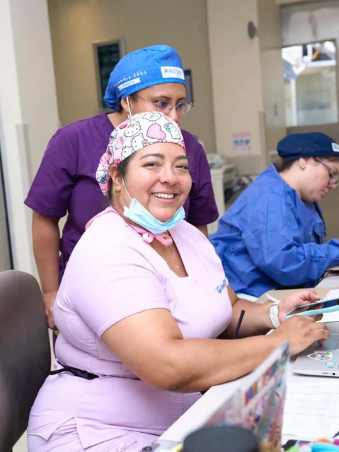 Female volunteer sits at the medical desk, writing patient notes in their files.