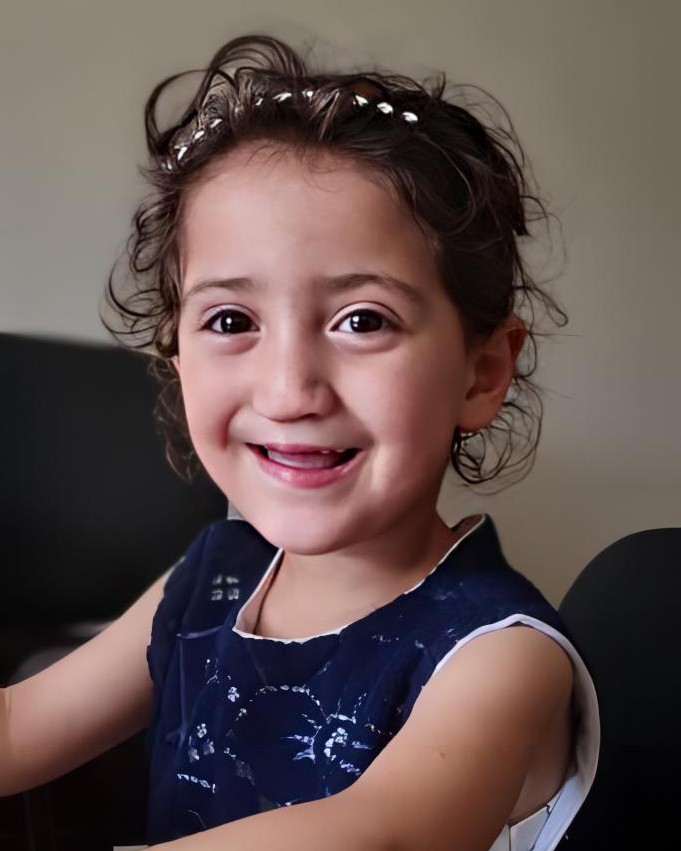 A young girl poses for the camera and smiles.