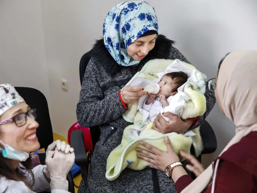 Dentists and mother watch baby bottle feed for the first time