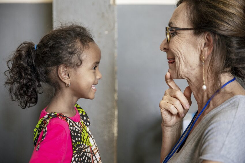 A young girl and woman face and mirror each other’s facial expressions.