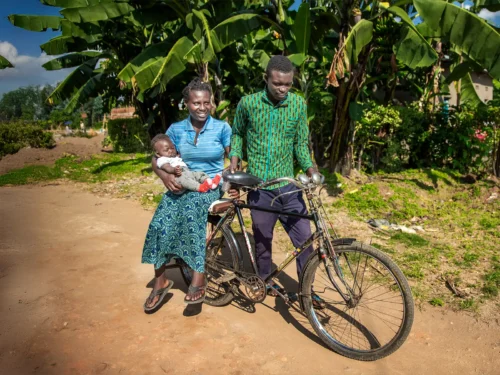 Adolphe Nezerwa, 6 months in his mothers arms riding on the back of a bicycle with his dad