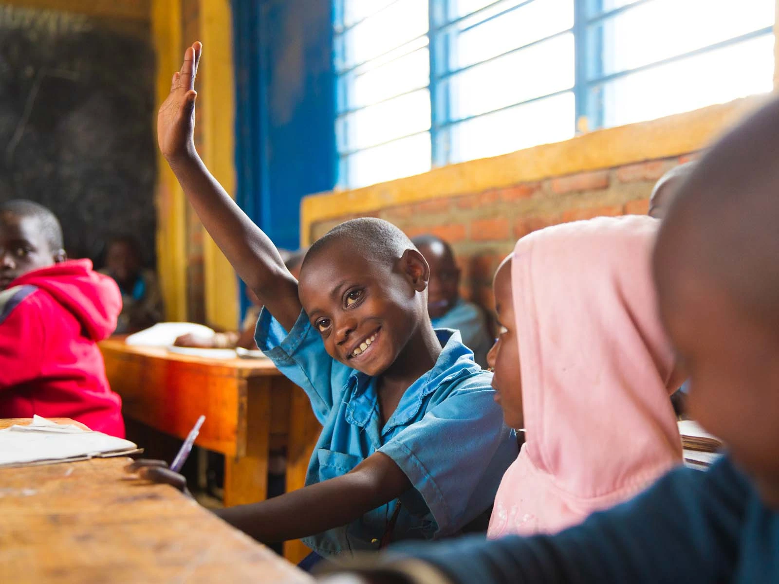 Valentine from Rwanda raising her hand in the classroom