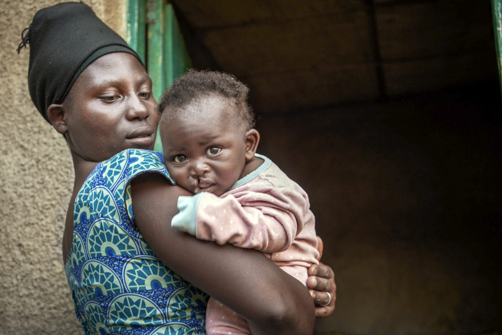 Mother holding her son standing in front of their home