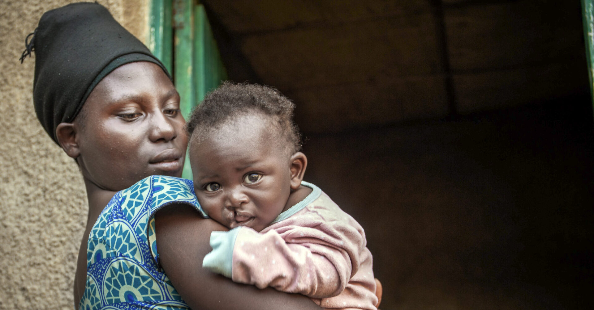 Mother holding her son standing in front of their home