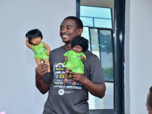 A volunteer from Rwanda demostrating 2 cleft dolls