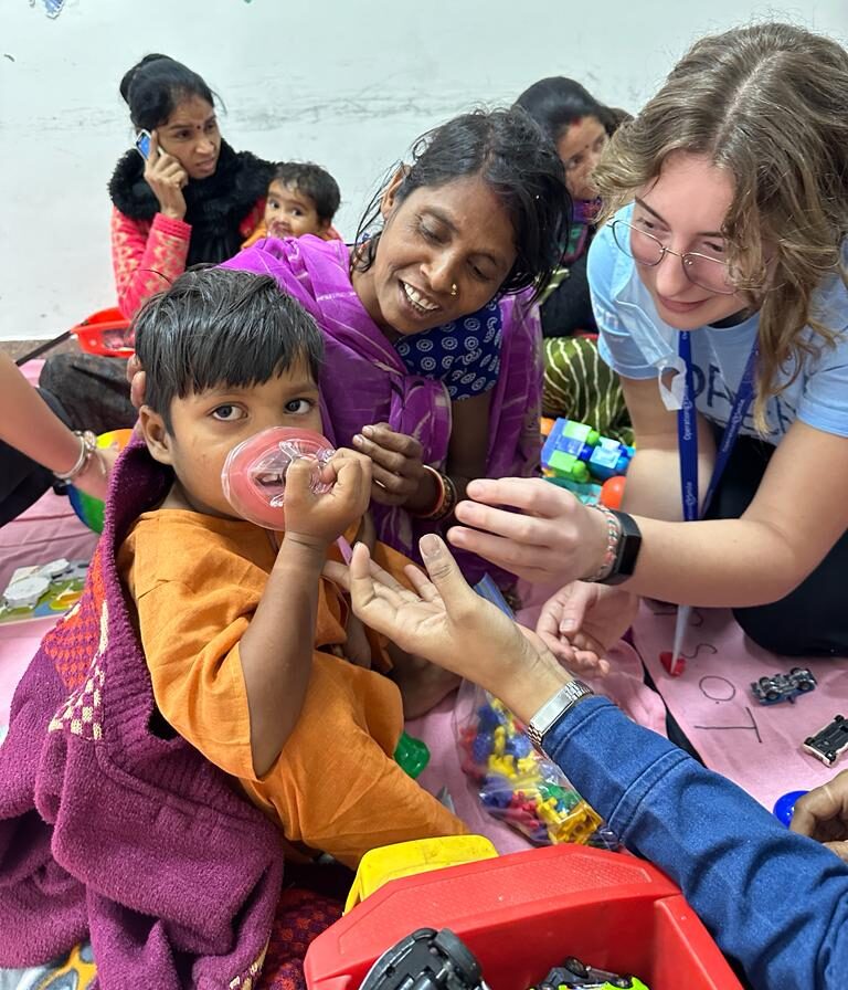 Canadian student volunteer interacting with child and mother from India before surgery