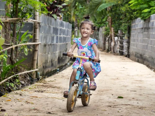 Young girl from Thailand riding her bicycle on a dirt road.
