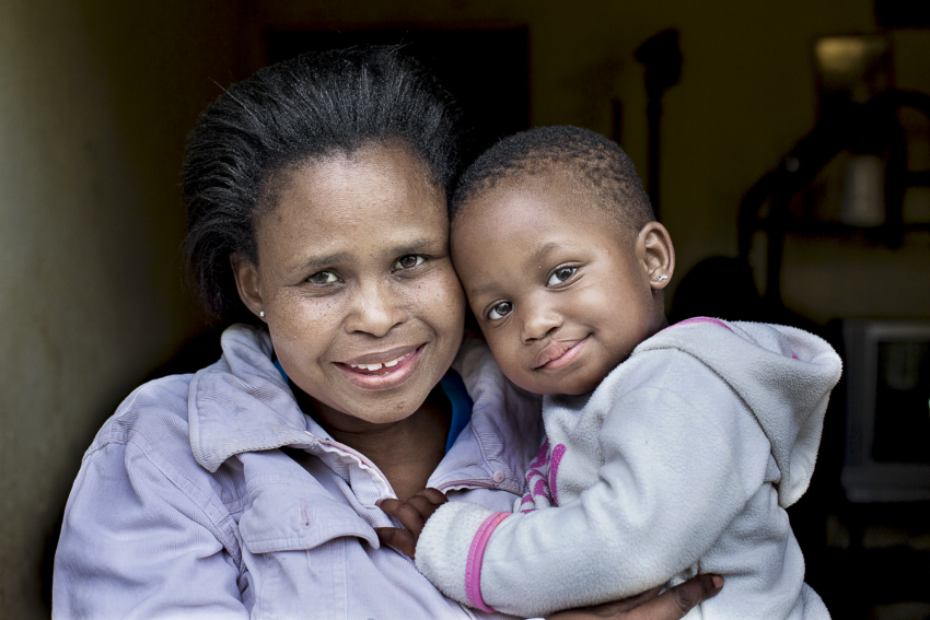 female, 2-year-old girl from Mbombela, South Africa, cuddles in her mother’s arms, both smiling happily after her successful cleft lip surgery.